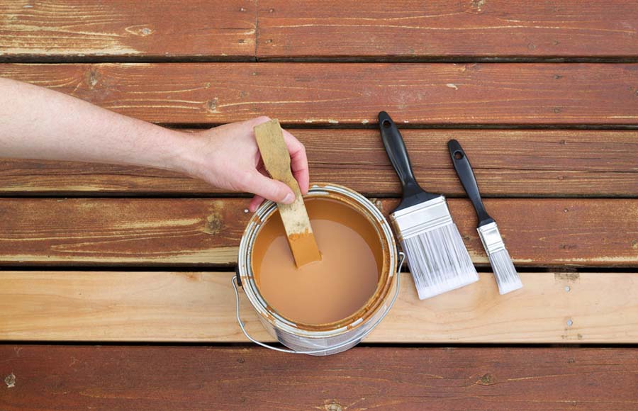 Une personne remue de la peinture pour la terrasse