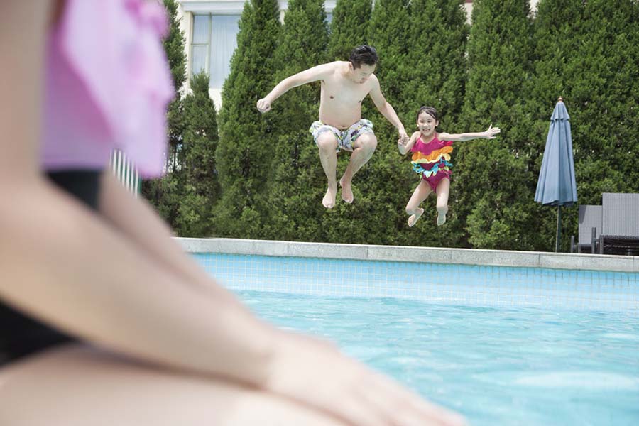 Father and daughter jump into swimming pool together