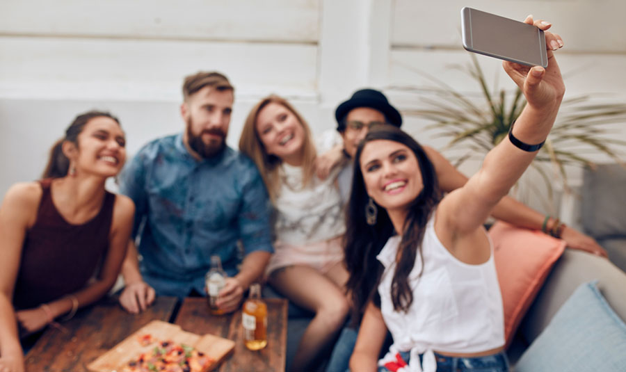 Group of young adults taking a group selfie on the couch