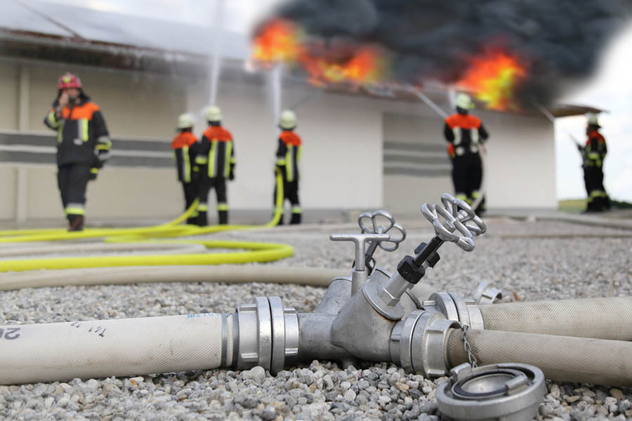 Des pompiers luttent contre un incendie à l’aide d’un tuyau à incendie