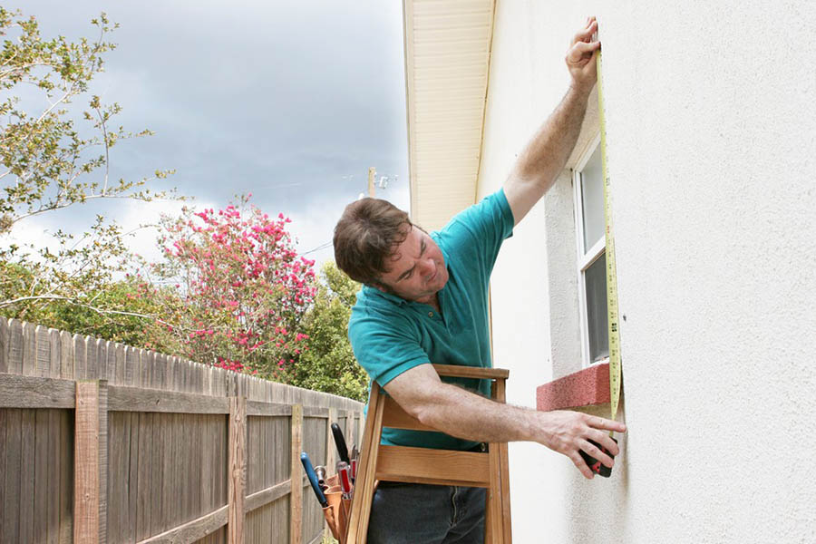 Person works on windows on exterior of a house