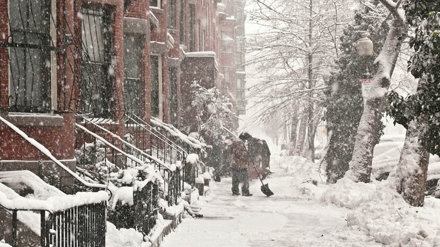 People clearing the sidewalks of ice and snow in a city