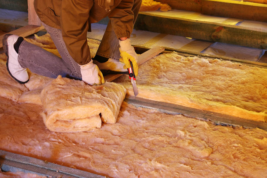 Person cutting insulation while they install it