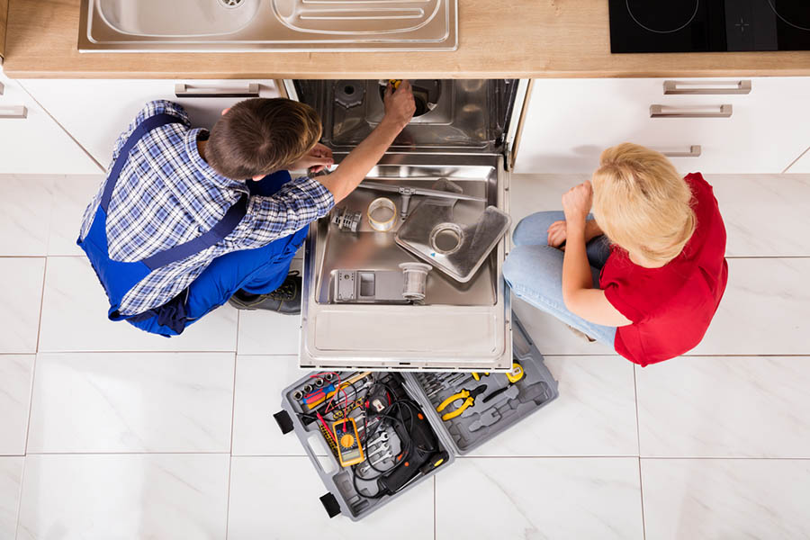 Man and women working on sink plumbing with tools