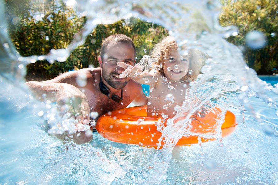 Father and daugther playing in a pool, splashing around