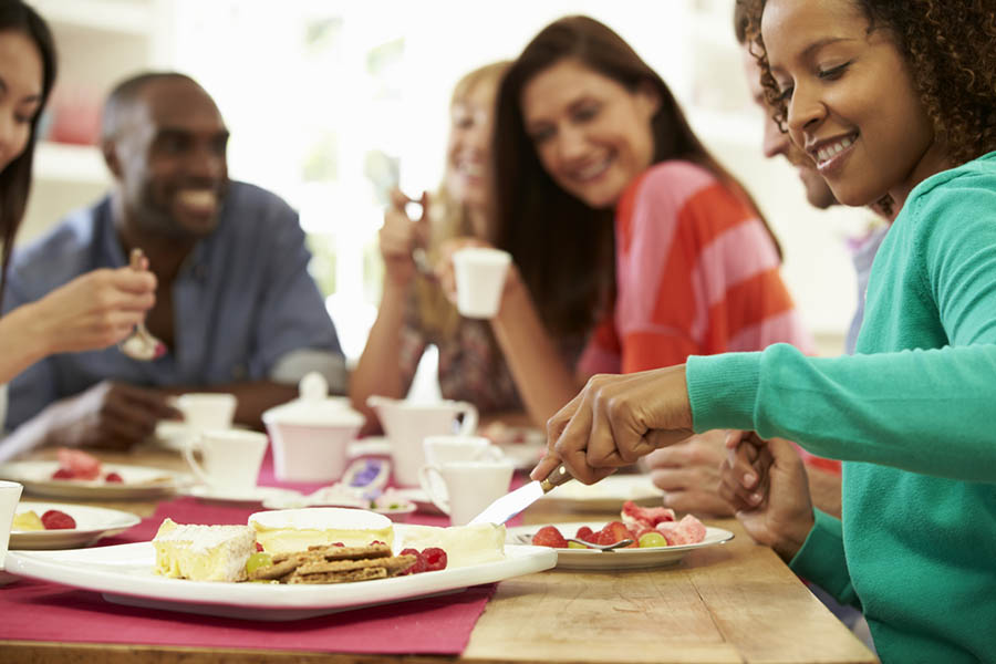 Group of happy people sitting together and eating snacks