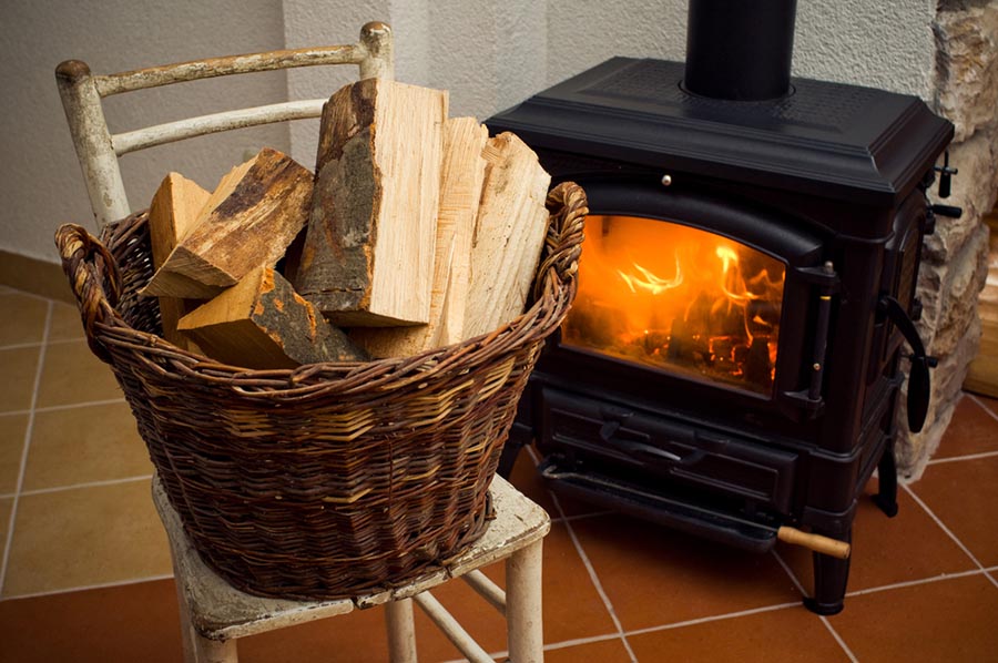 Un tas de bois découpé à côté d’un poêle à bois