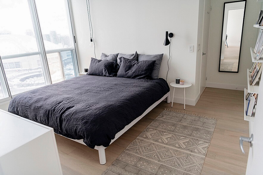 Scandinavian minimalist bedroom with a mirror next to the door