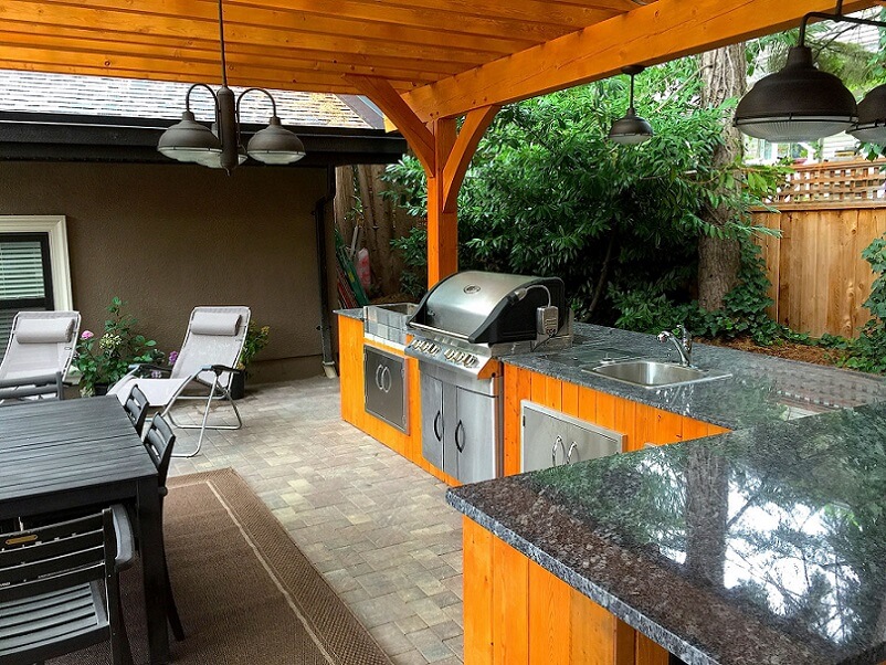 Outdoor kitchen with stone countetops and wood roof