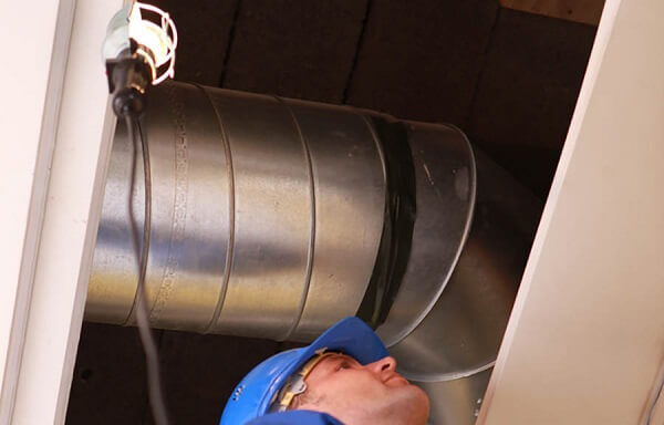 HVAC repair man inspecting the back of an HVAC