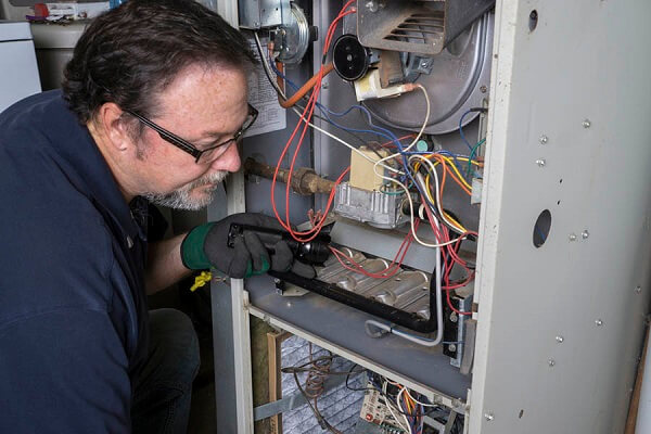 HVAC repair man inspecting the back of an HVAC