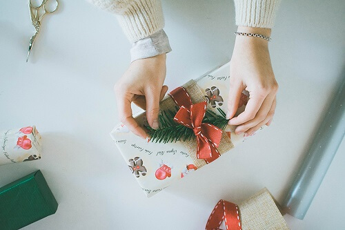 Women completes wrapping present with pine