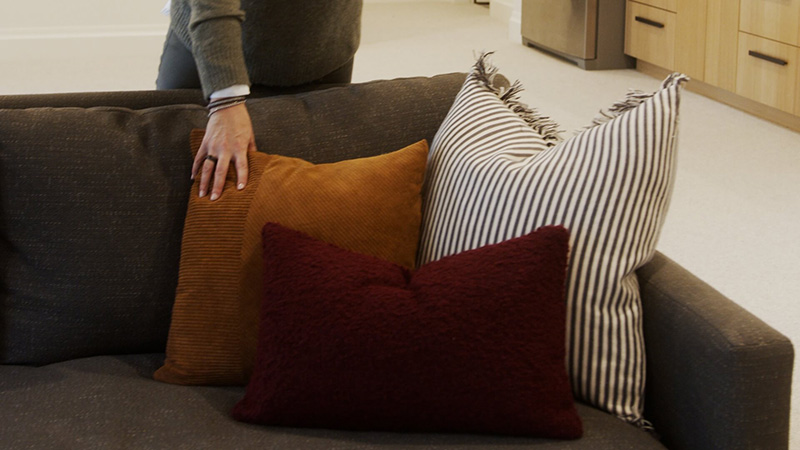 Three different size throw pillows arranged on a sofa