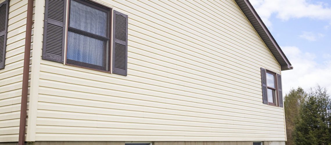 Le mur d’une maison revêtue de bardage de vinyle en blanc cassé