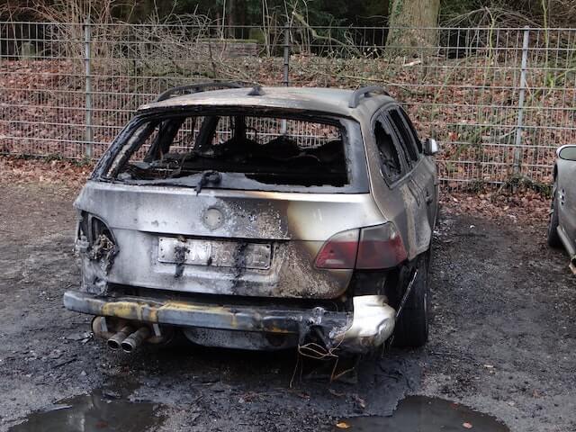 A small grey car that's been severely damaged by fire