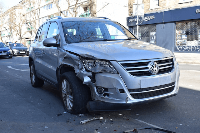 A grey SUV with damage to the front fender and headlight