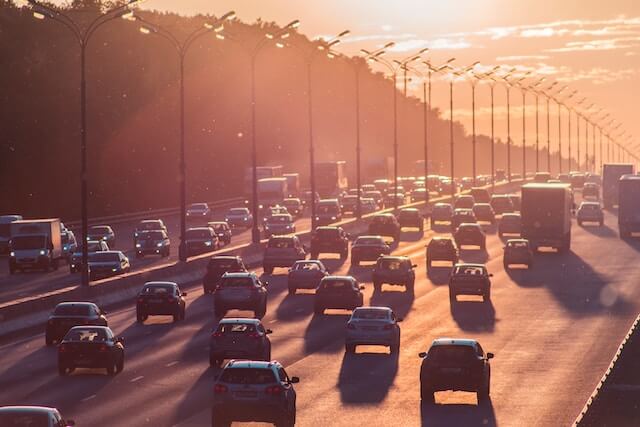 Wide shot of a busy freeway at sunset, full of cars