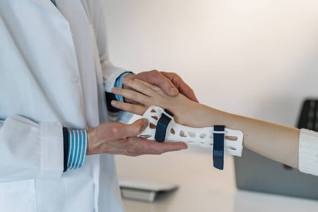 An arms-only image of a doctor applying a brace to an injured patient's wrist