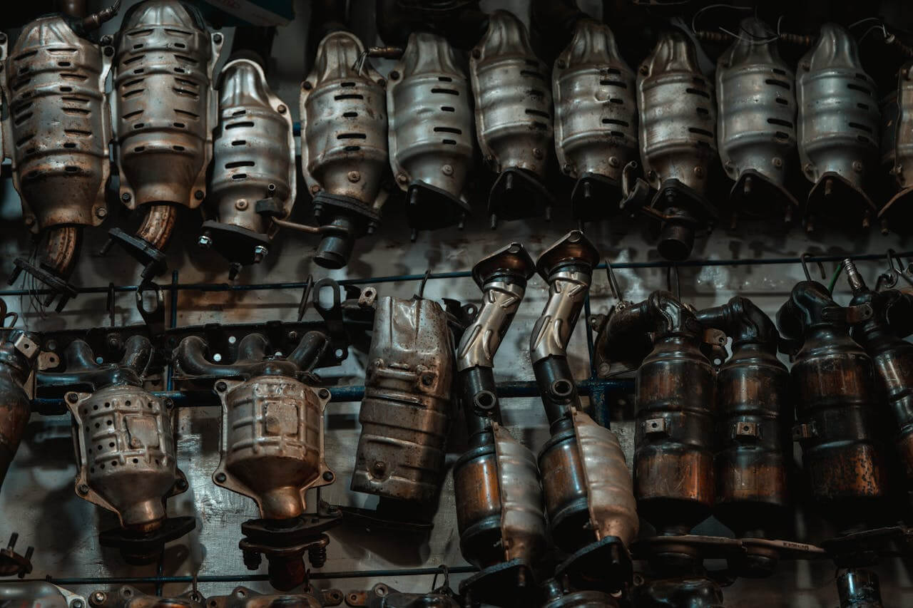 Rows of used catalytic converters in an automotive workshop setting