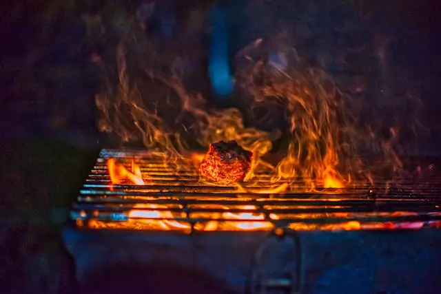 A steak sits on an outdoor grill, surrounded by flames